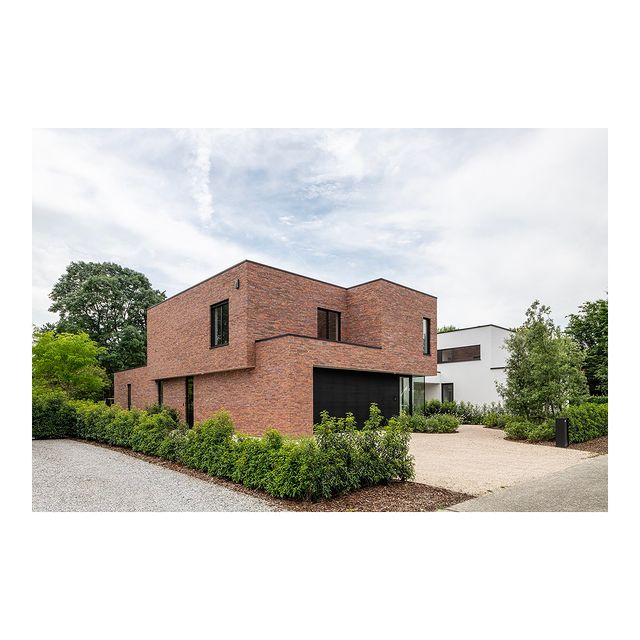 Deze woning werd gerealiseerd met een warme bruinrode gevelsteen in contrast met het zwarte schrijnwerk. De speelse volumewerking door een uitkraging aan de zijgevel en een insprong aan de voorgevel geven de woning een dynamische uitstraling.
De achtergevel werd opengewerkt naar de tuin en voorzien van een overdekt terras die aansluit op het leefgedeelte. De kolommen zorgen voor een visueel doorzicht naar de tuin en vormen de begrenzing van het terras aansluitend op de plantenzone.

Architecture and interior design by CH-Architecten
@michielvergauwe_photography

#brickarchitecture #baksteenarchitectuur #belgianarchitecture #belgischearchitectuur #itsallinthedetails #modernearchitectuur #modernliving #highendarchitecture #warmmaterials #villa #house #interieurarchitectuur #interiordesigns #blackdetails